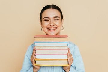 student in denim shirt with books smiling isolated on beige