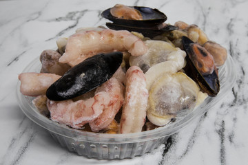Frozen goods. Seafood. Closeup of raw shrimps, prawns, mussels, scallops, oysters and cockles ready for cooking.