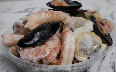 Frozen goods. Seafood. Closeup of raw shrimps, prawns, mussels, scallops, oysters and cockles ready for cooking.  
