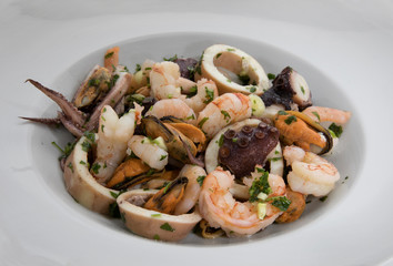 Gourmet. Traditional mediterranean seafood dish with Provencal condiment, garlic and parsley. Spicy shrimps, squid, prawns and mussels in a white dish.