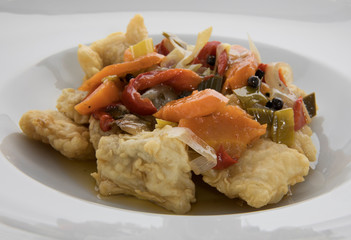 Gourmet food. Fish with marinade sauce. Closeup of pickled breaded and fried hake with vegetables.