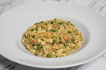 Chinese cuisine. Chow fan with shrimps, peas, rice, eggs and carrot in a white dish. 