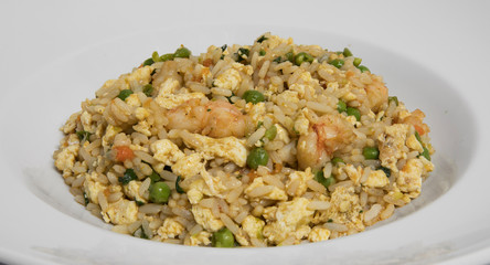 Chinese cuisine. Closeup view of a shrimp Chow Fan, with rice, peas, egg yolks and carrot, served in a white dish. 