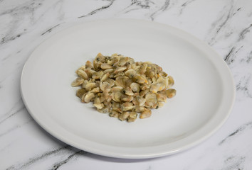 Gastronomy. Seafood ingredient. View of cockles on a white dish on the table. 