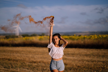 Chica feliz en campo con bomba de humo