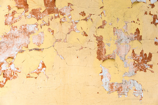 Old cracked yellow wall with red spots as background.