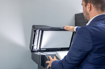 Man dressed in blue suit taking a photocopy in the office