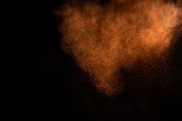 Fototapeta na wymiar Orange powder explosion on black background. Colored powder cloud. Colorful dust explode. Paint Holi.