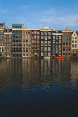 Beautiful canal houses in Amsterdam during sunset with calm reflection in the water