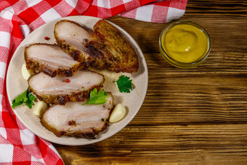 Baked pork belly in a plate on wooden table. Top view