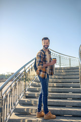Smiling man with coffee standing turning around on steps