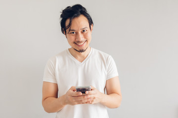 Happy long hair Asian man in white casual t-shirt is using smartphone.