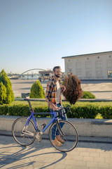 Vigorously walking man with bike on sunny day