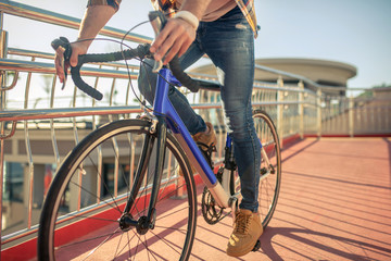 Male legs in jeans on pedals of riding bike