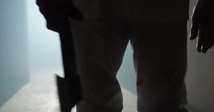 Maniac carrying a murderous weapon escaping from crime scene. Bloodthisty criminal carrying an axe in hallway of old house 4k footage