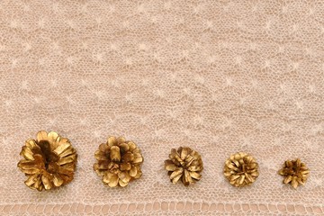 Delicate background five golden cones horizontal next to in descending size order on the knitted...