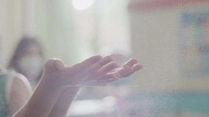 This close-up clip shows a person spraying a child's hands with a sanitizing solution, then having the kid rub the cleaning spray into their hands. - Powered by Adobe