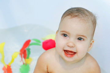 Little girl bathing in the bathroom. The child washes in a basin with toys