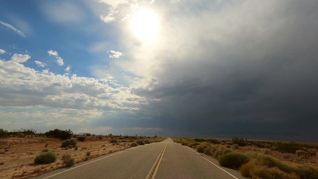 Driving down a lonely, empty road in the countryside as rain clouds roll in - driver point of view