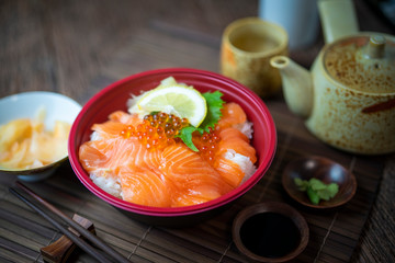 Delicious Donburi or Japanese rice bowl topped Sashimi Salmon Roe and Fish eggs on Bamboo table.