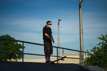 Chico joven con perilla y mascarilla en skate park