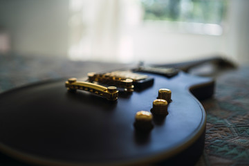 Guitarra negra y dorada sobre una cama