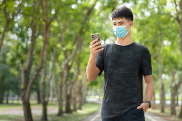 Portrait of smiling and cheerful young Asian man relaxing in the park with protective face mask to prevent virus infection or hay fever.Hope concept or Positive Emotion..