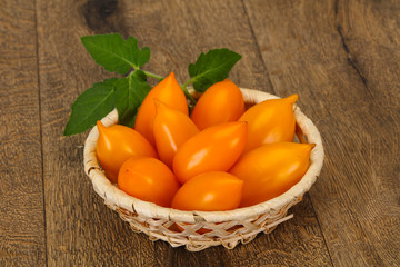 Yellow tomato heap in the wooden bowl