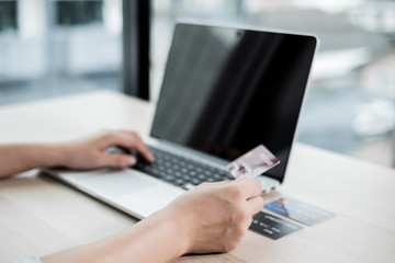 The businesswoman's hand is holding a credit card and using a laptop for online shopping and internet payment in the office