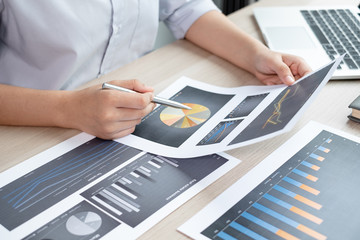 The hands of a male businesswoman are analyzing and calculating the annual income and expenses in a...