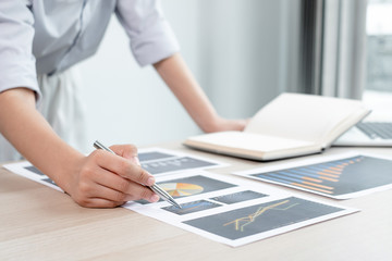 The hands of a male businesswoman are analyzing and calculating the annual income and expenses in a financial graph that shows results To summarize balances overall in office