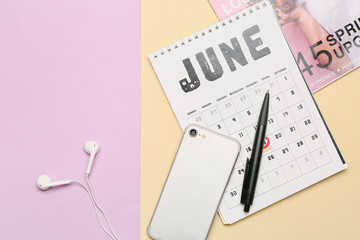 Mobile phone with calendar and magazine on color background