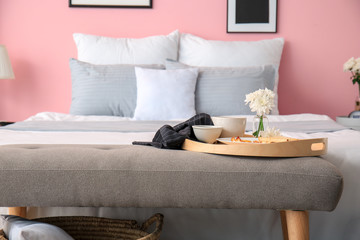 Tray with breakfast on bedside bench in interior of modern room