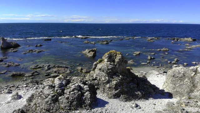 Aerial view around a limestone Rauk, rock formation, on the coast of Faro island, sunny day, in Gotland, Sweden - Orbit, drone shot