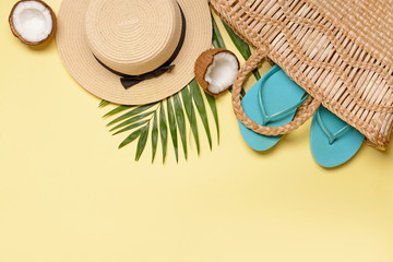 Straw hat and bag with flip-flops on color background