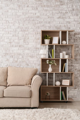 Wooden rack and soft sofa near brick wall in room