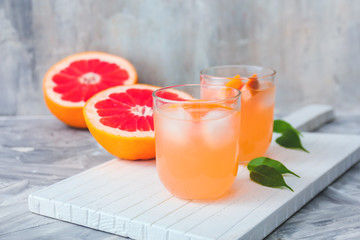 Glasses of fresh grapefruit juice on grey background