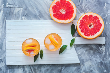 Glasses of fresh grapefruit juice on grey background