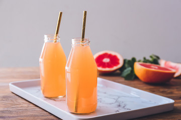 Fototapeta premium Bottles of fresh grapefruit juice on table