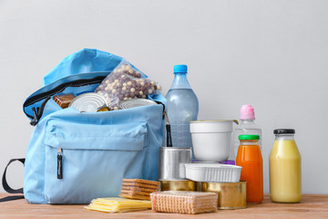 Schoolbag with different products on table. Concept of Backpack Food Program