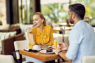 Smiling woman enjoying in dessert while being with her boyfriend in a cafe.