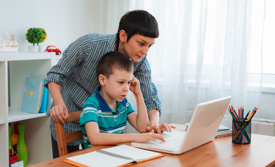 Mother and child school student at home on a laptop learning homework. e-home schooling during the...
