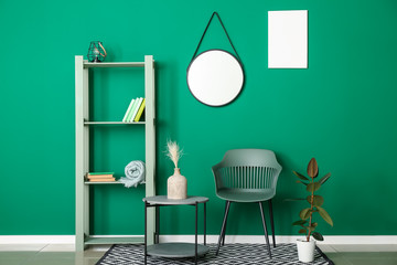 Armchair with table and rack near color wall in room
