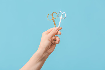 Female hand with manicure scissors on color background