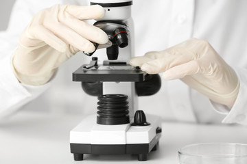 Scientist using microscope in laboratory, closeup