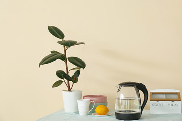 Electric kettle, cup of tea and lemon on kitchen table