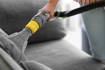 Woman removing dirt from sofa at home