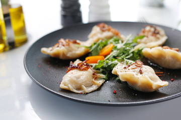 Traditional dumplings. Traditional homemade meat dumplings served on a black plate. Suggestion to serve the dish. Top view.