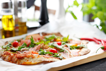 Italian pizza with ham. Traditional Italian pizza with Parma ham, cherry tomatoes and arugula.