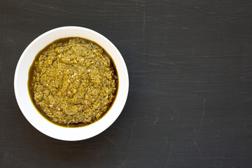 Homemade Basil Pesto with Parmesan and Pine Nuts on a black background, top view. Flat lay, overhead, from above. Space for text.